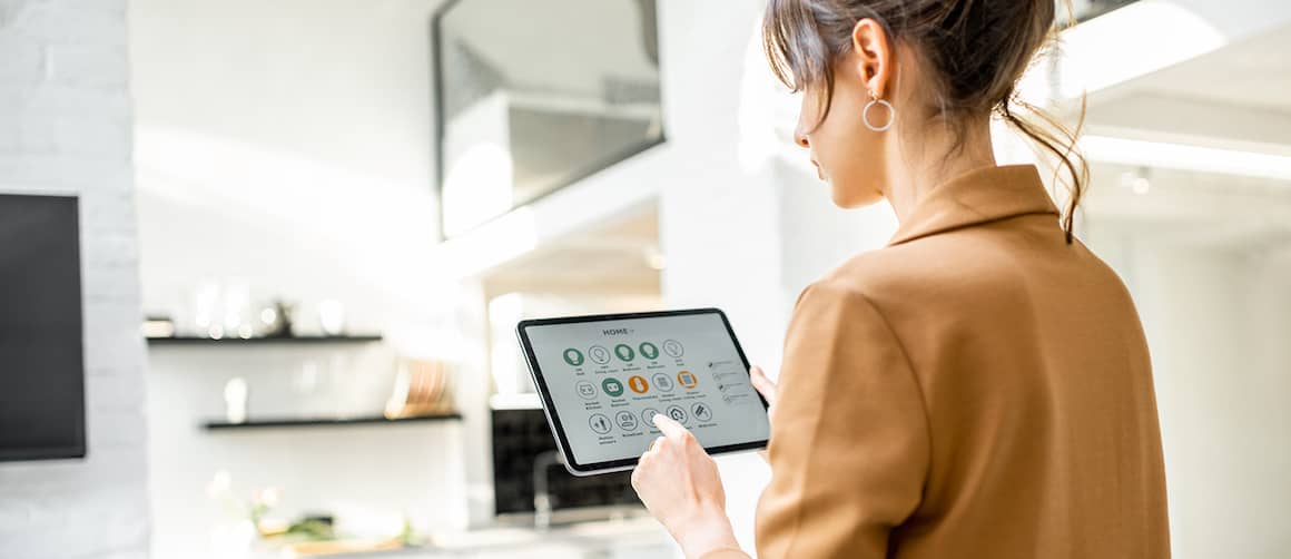 A woman viewing a smart home hub device, suggesting the concept of smart home technology and control.