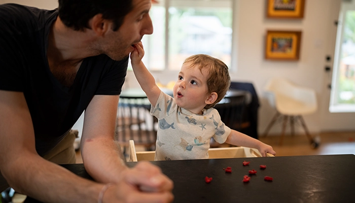 Kid placing food in parent's mouth.