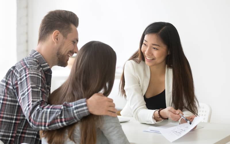 Agent talking to couple and explaining a document.