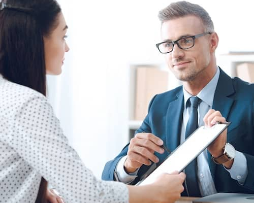 Two individuals discussing paperwork in an office setting.