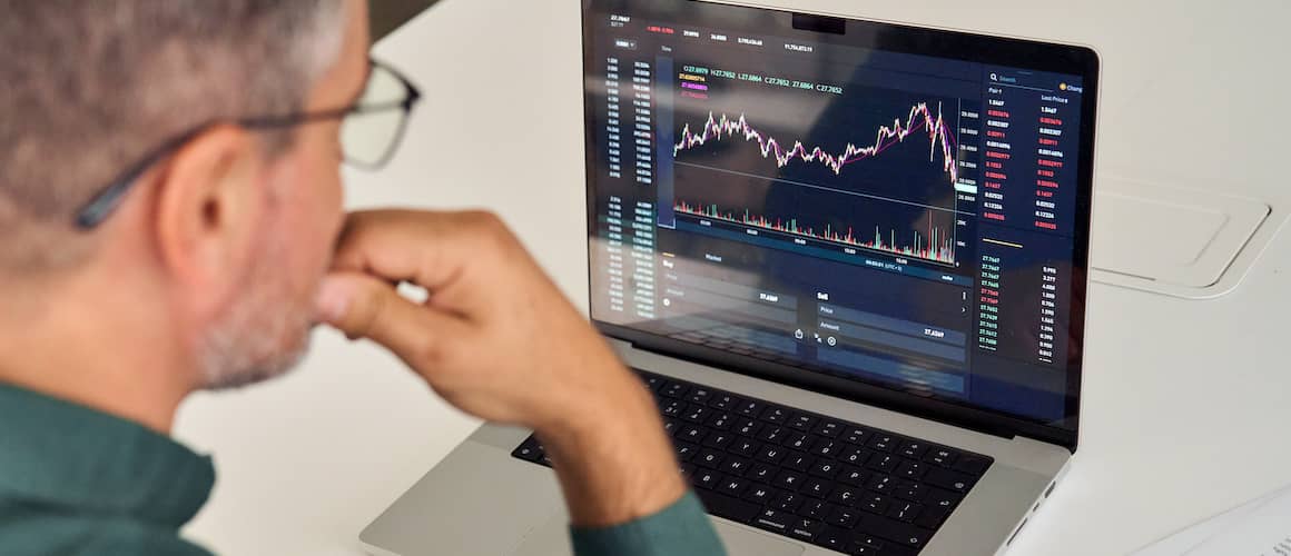 Man in suit reviewing stock market charts and numbers.