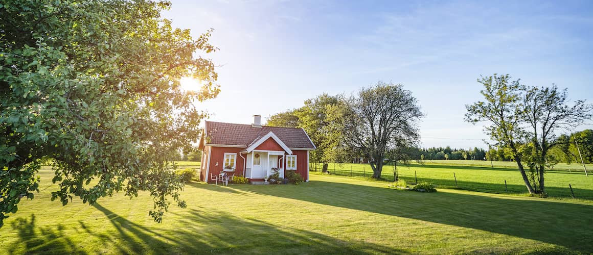 Small vivid red brick house with white door/window trim and lush green lawn.