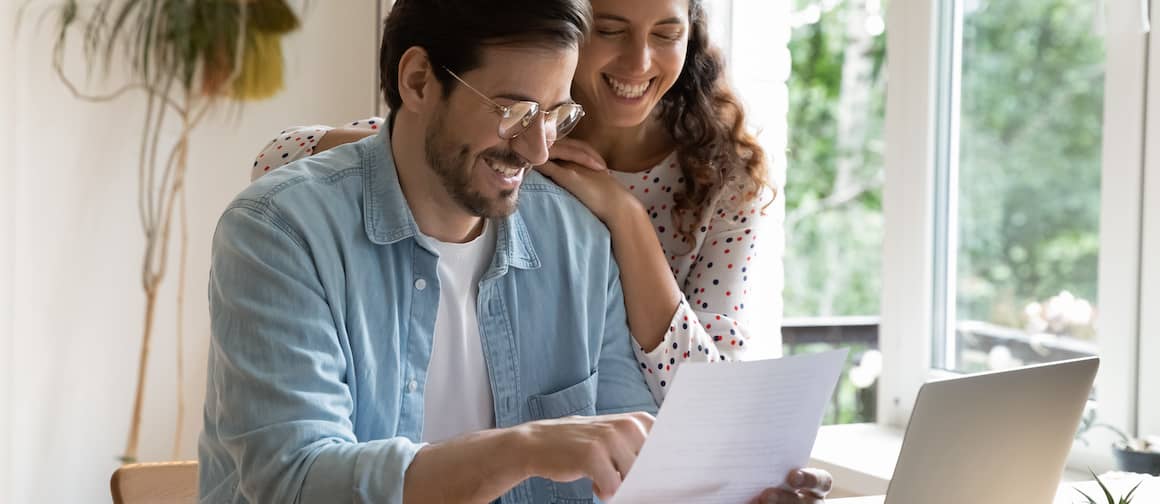 Man and woman sitting at table, reviewing document and smiling.