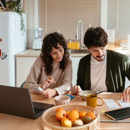 Couple eating breakfast together while going over annual budget.