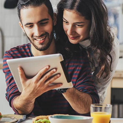 A couple looking at an iPad in a kitchen.