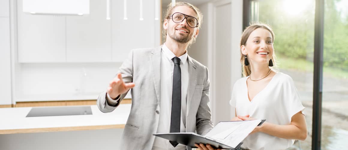 A real estate agent with a file showing and describing a house to a woman.