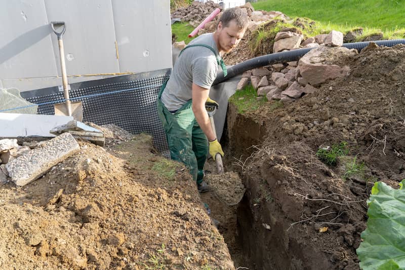 Man digging up yard to install a French drain.