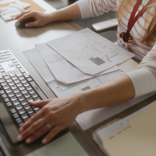 Team member typing at a desk filled with papers.