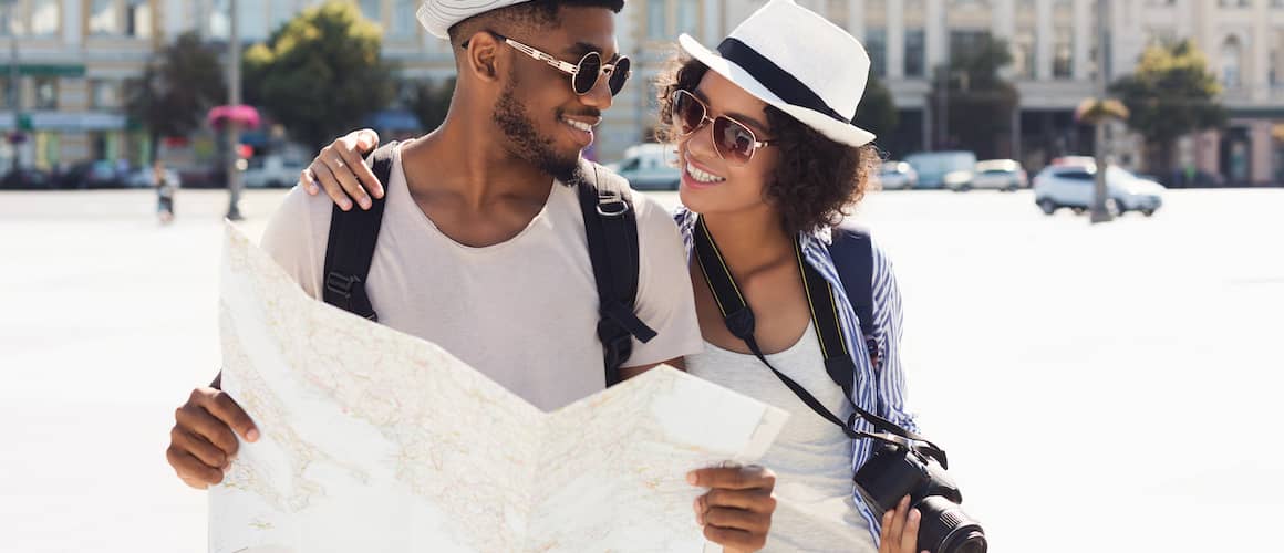 Young couple on vacation together abroad looking at map together and smiling.