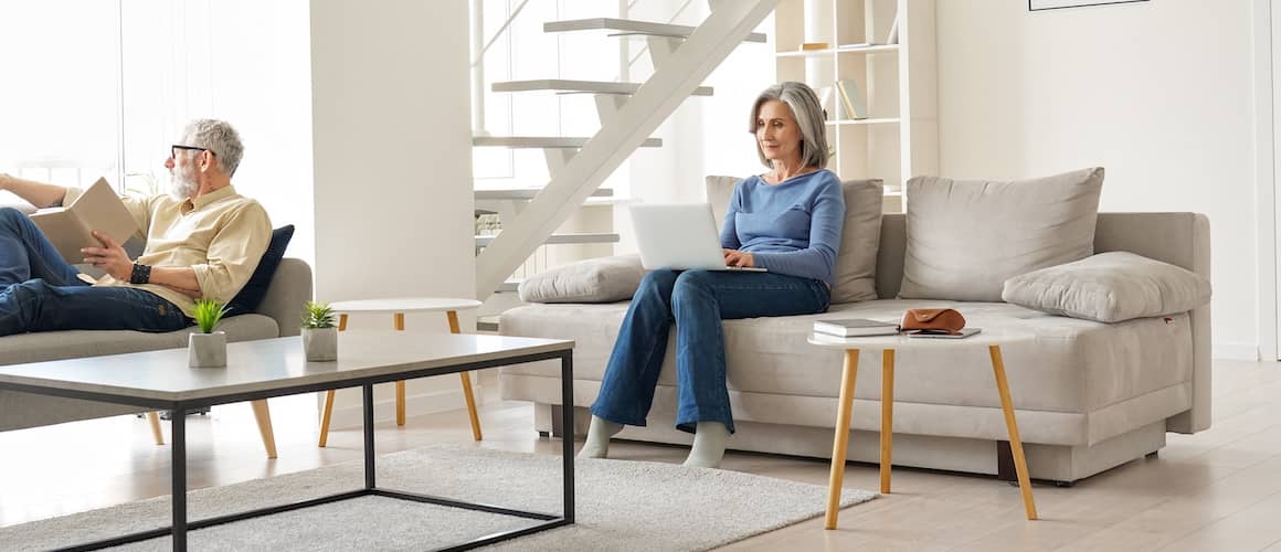 A senior couple relaxing on couches in a living room, indicating a comfortable and relaxed retirement setting.