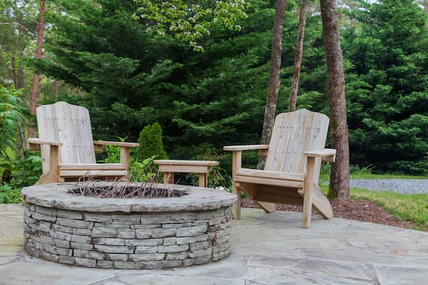 Two Adirondack chairs around a brick fireplace.