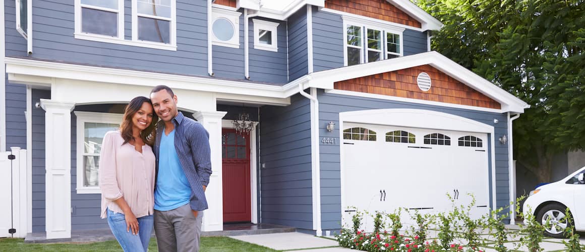 Couple standing in front of their new home, expressing excitement and happiness.