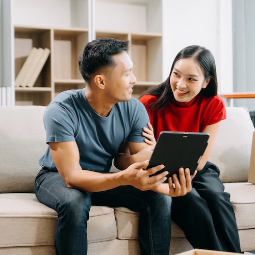 Young couple looking at tablet on couch while taking a break from shopping.