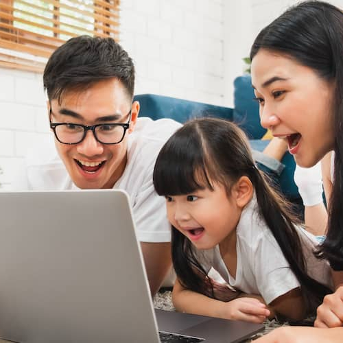 A happy family of three gathered around a laptop, enjoying quality time together while browsing online.