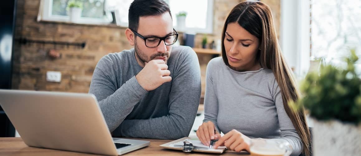 A couple looking at papers in a house, potentially discussing documents related to homeownership or a real estate purchase.