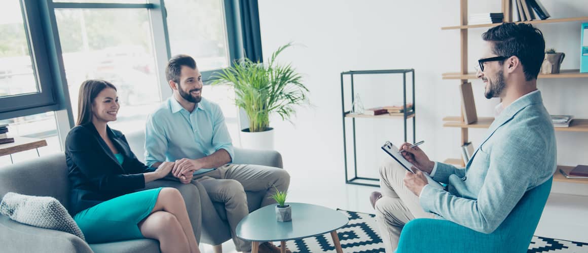 couple holding hands in meeting with doctor